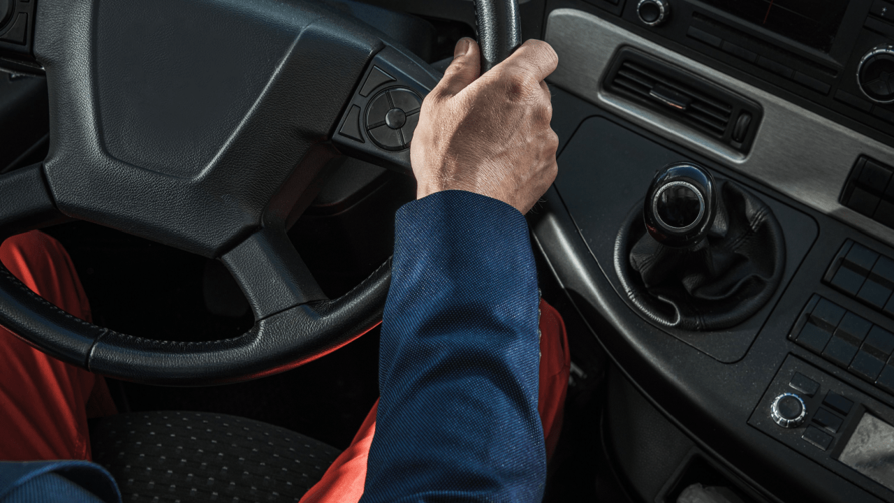 Truck driver hand on steering wheel in commercial cab learning what is a CMV violation