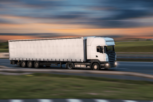 Commercial truck driving on highway at dusk representing what is the most common DOT violation in trucking industry