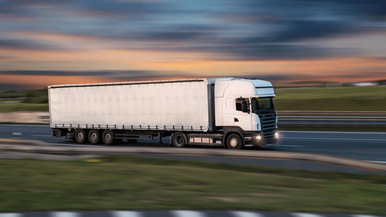 Commercial truck driving on highway at dusk representing what is the most common DOT violation in trucking industry