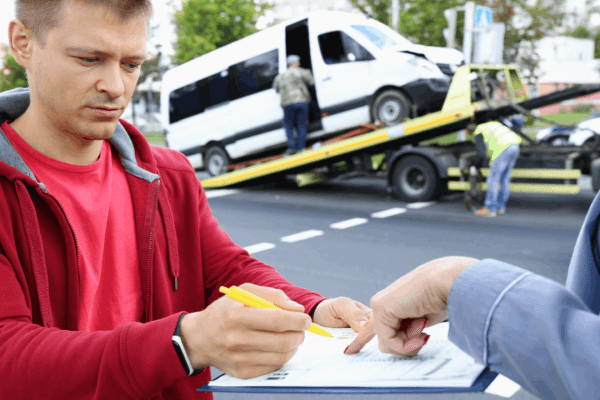 Truck accident victim documenting factors that increase a truck accident settlement with an insurance representative at the collision scene with damaged vehicles
