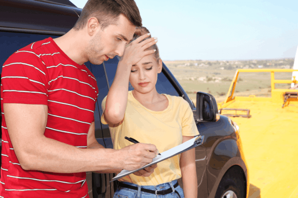 Truck accident settlement process begins as stressed couple exchanges insurance information after highway collision