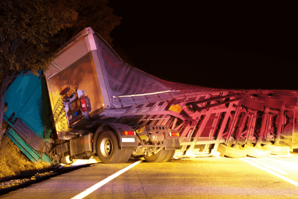 Overturned commercial truck accident scene at night showing does liability mean responsibility in a truck accident