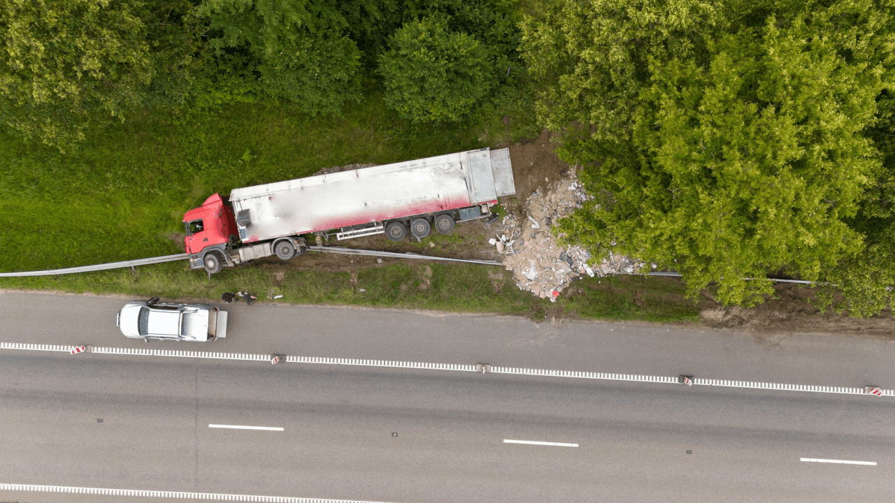 Truck accident liability scene with overturned tanker truck off roadway, debris field, and emergency response investigation