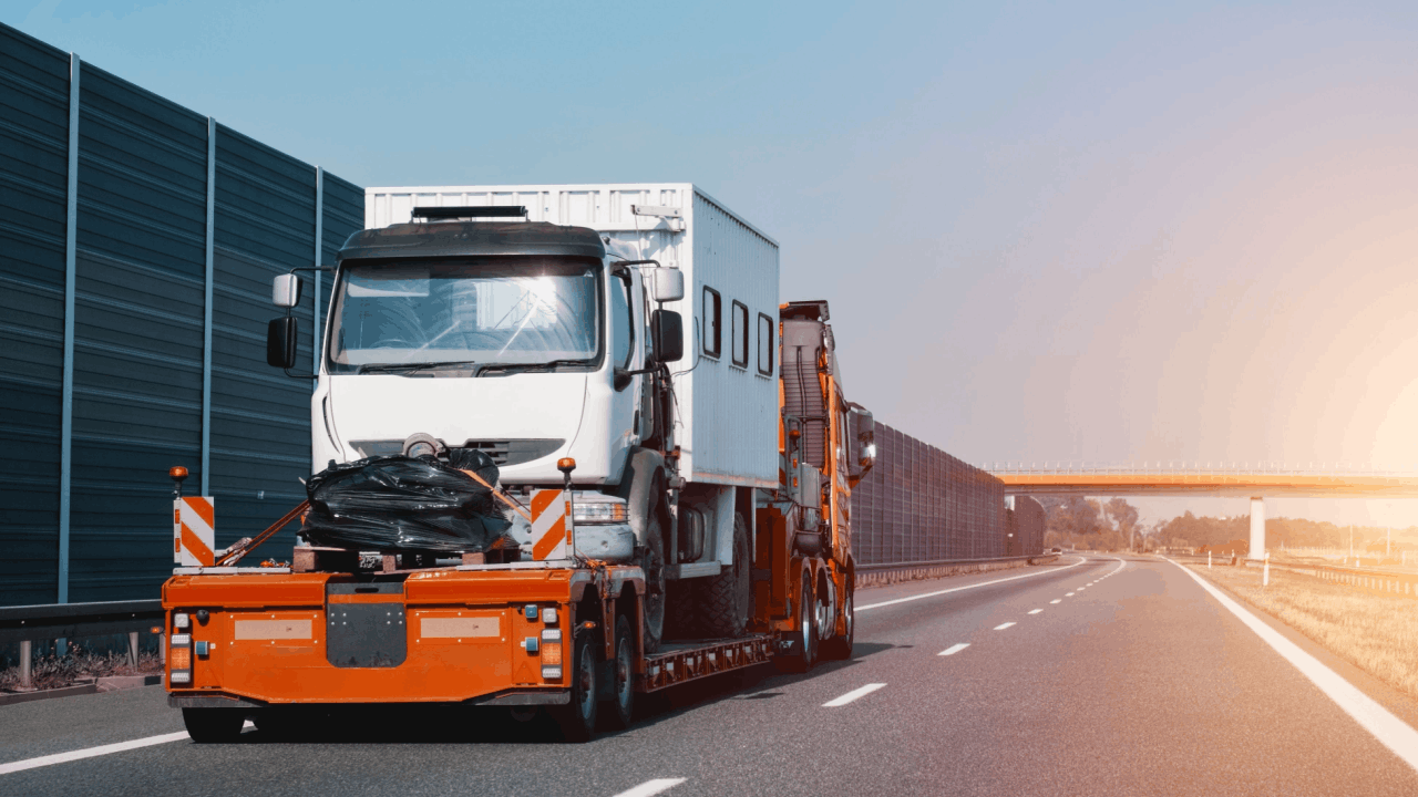 Commercial tow truck transporting damaged vehicle on highway illustrating does liability insurance apply if a truck driver is at fault claims