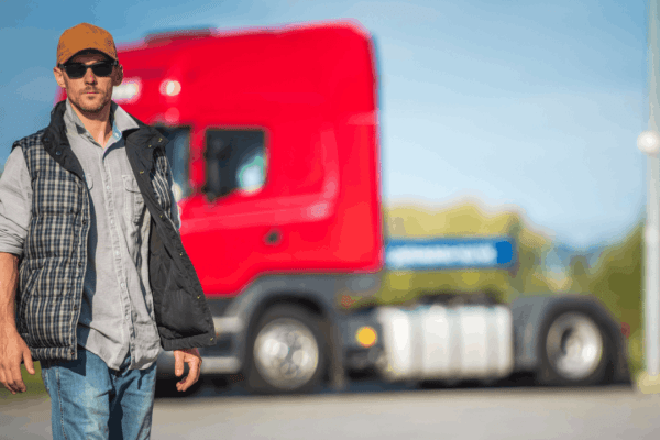 Truck driver standing in front of red commercial semi-truck representing employer liability in truck accidents cases