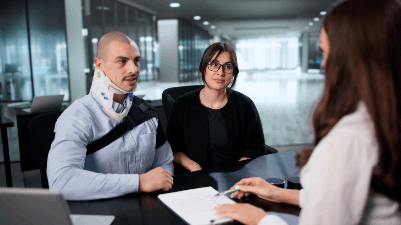 Injured man with neck brace and arm sling consulting a lawyer about truck accident compensation