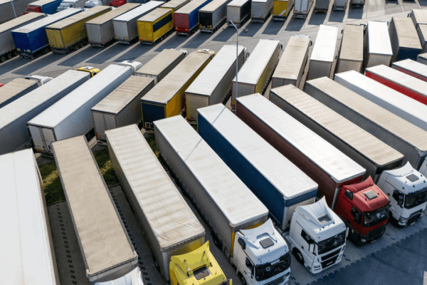 Truck driver vs trucking company liability concept with aerial view of commercial truck fleet at freight distribution center