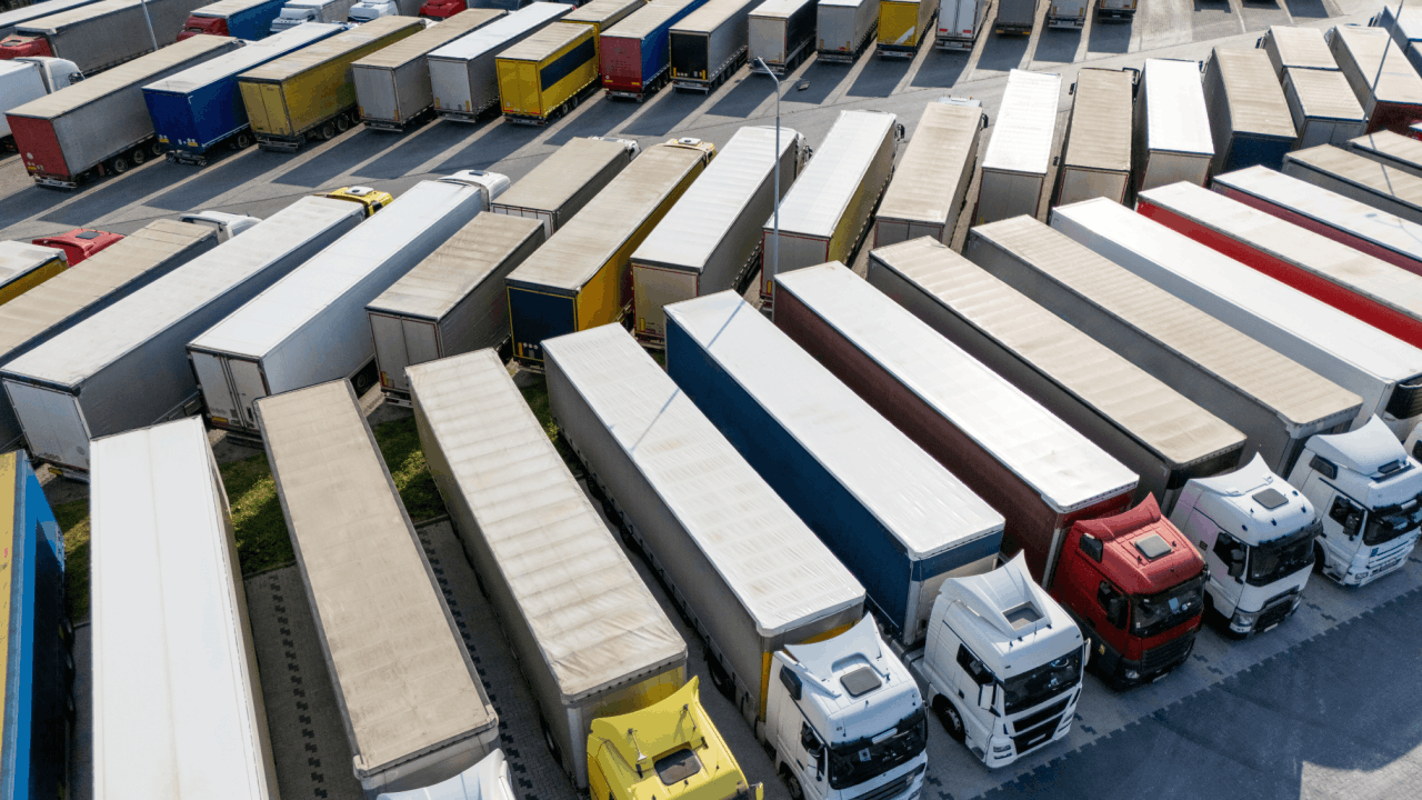 Truck driver vs trucking company liability concept with aerial view of commercial truck fleet at freight distribution center