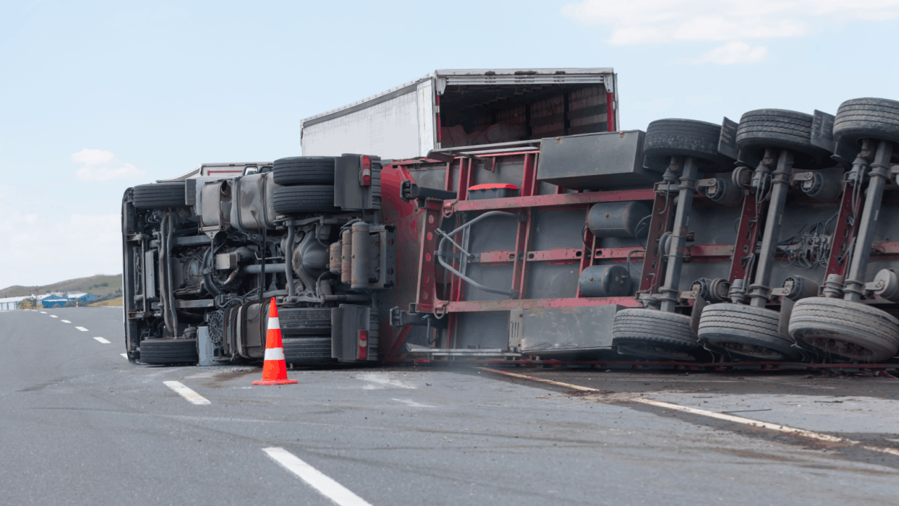 Overturned semi-truck on highway showing what not to say after a truck accident scene with emergency cones