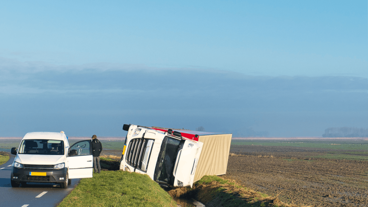 Overturned white commercial truck on roadside showing accident scene where determining who can be sued after a truck accident requires investigation