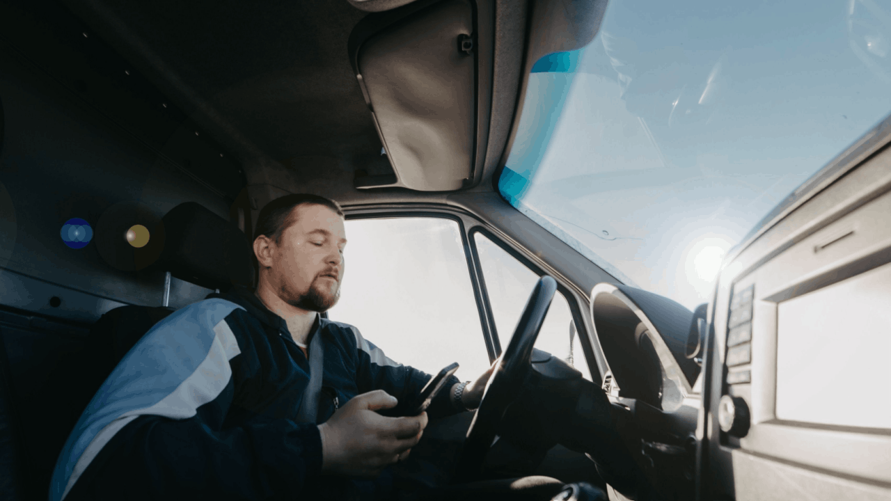Truck driver looking at phone while behind the wheel — distracted driving crashes risk