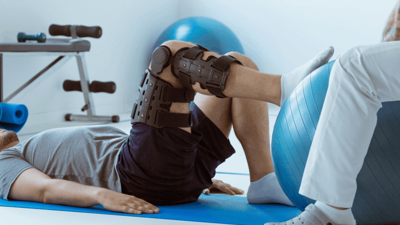 Rehabilitation after injury — physical therapist assisting truck accident victim with knee brace during recovery session