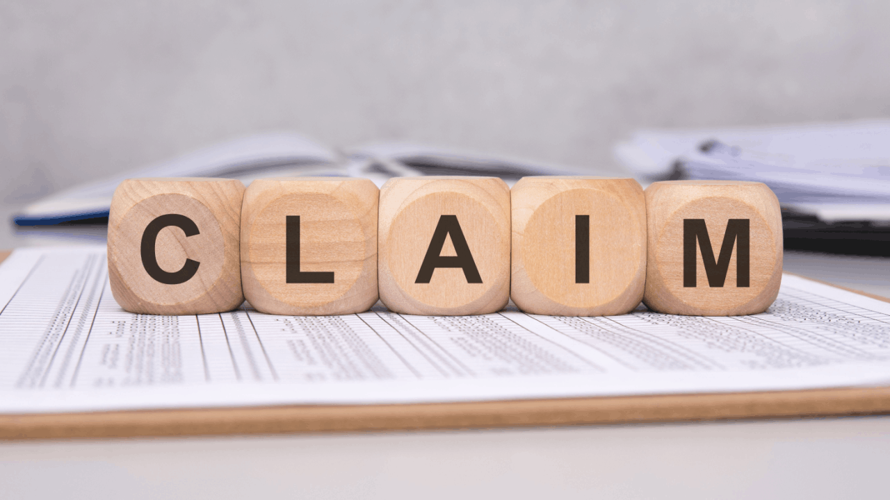 Wooden blocks spelling CLAIM on legal documents representing the trucking accident claim investigation process