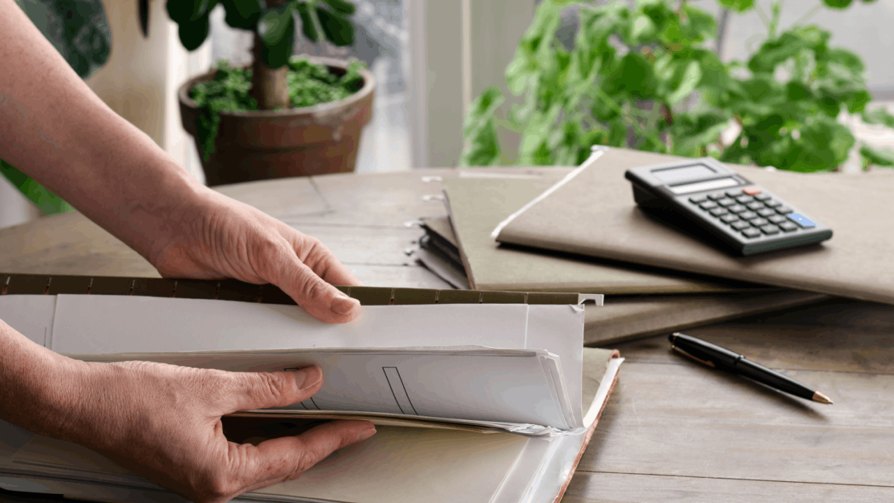 Filing a claim without a lawyer as a person sorts through paperwork in folders at a desk.
