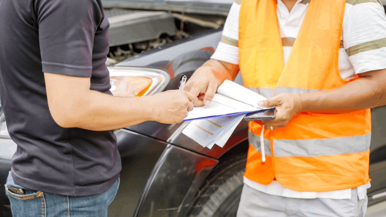 Truck accident claim eligibility being reviewed as a driver signs paperwork beside a damaged vehicle.