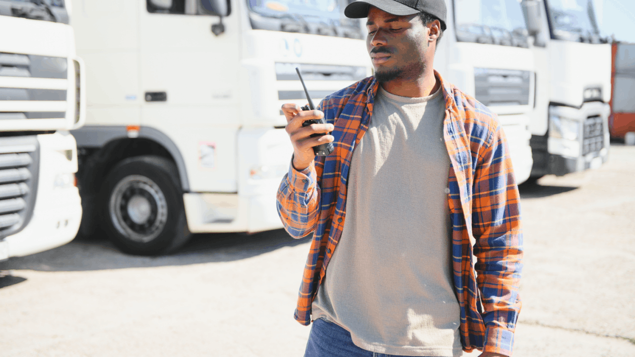 Truck driver using a radio near parked trucks, illustrating compensation when an unqualified driver causes a crash