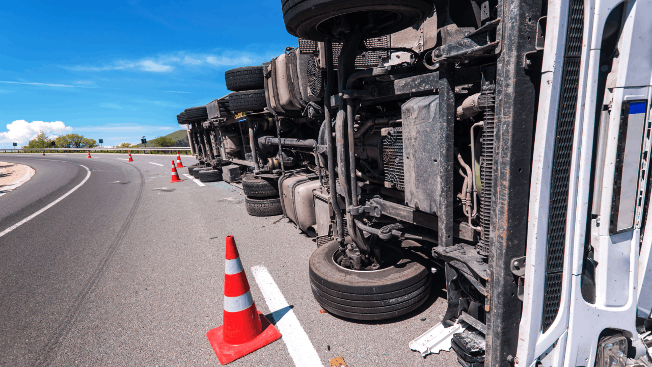 Overturned truck on highway showing who is liable when an unlicensed trucker causes a crash